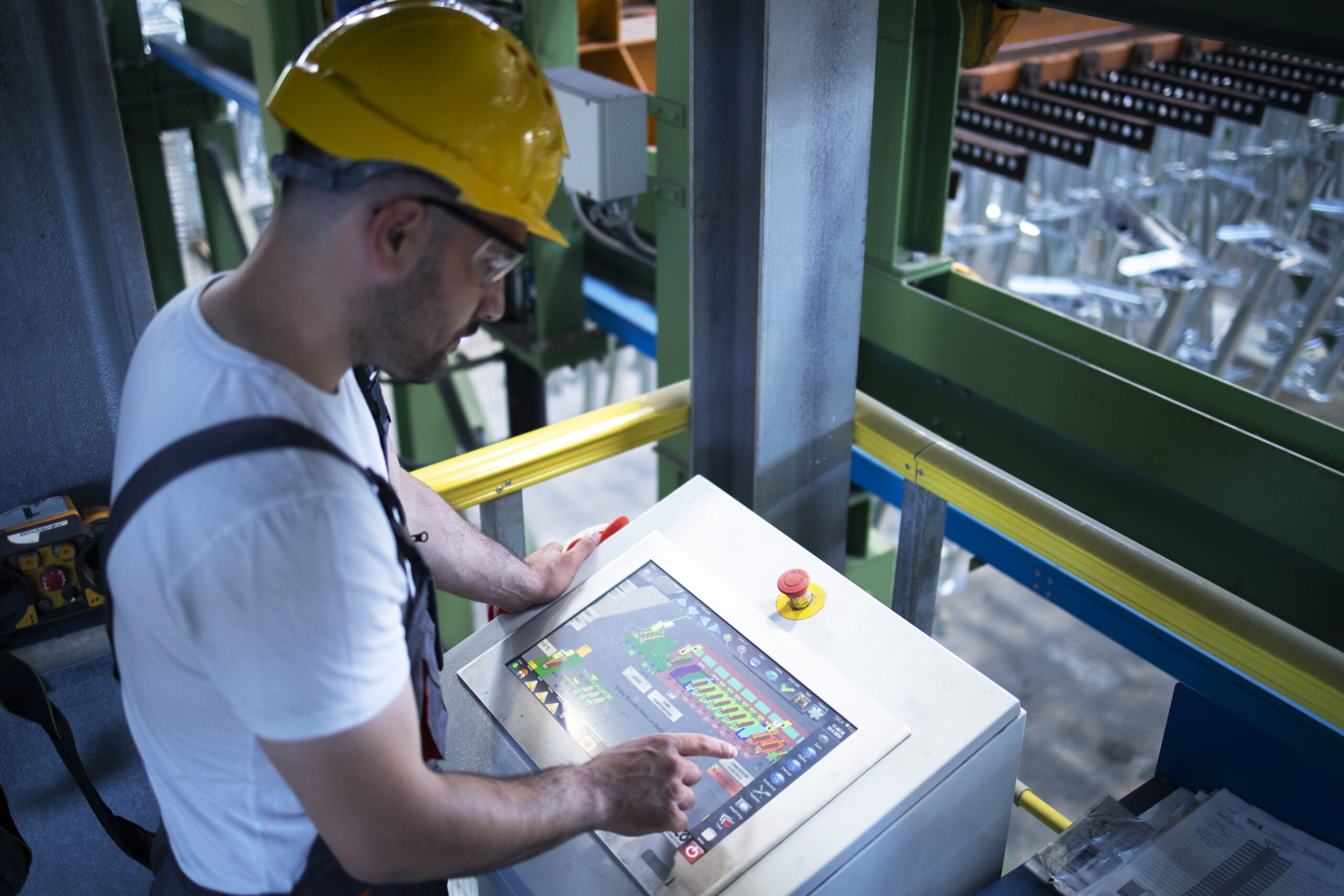 Factory worker monitoring industrial machines and production remotely in control room.